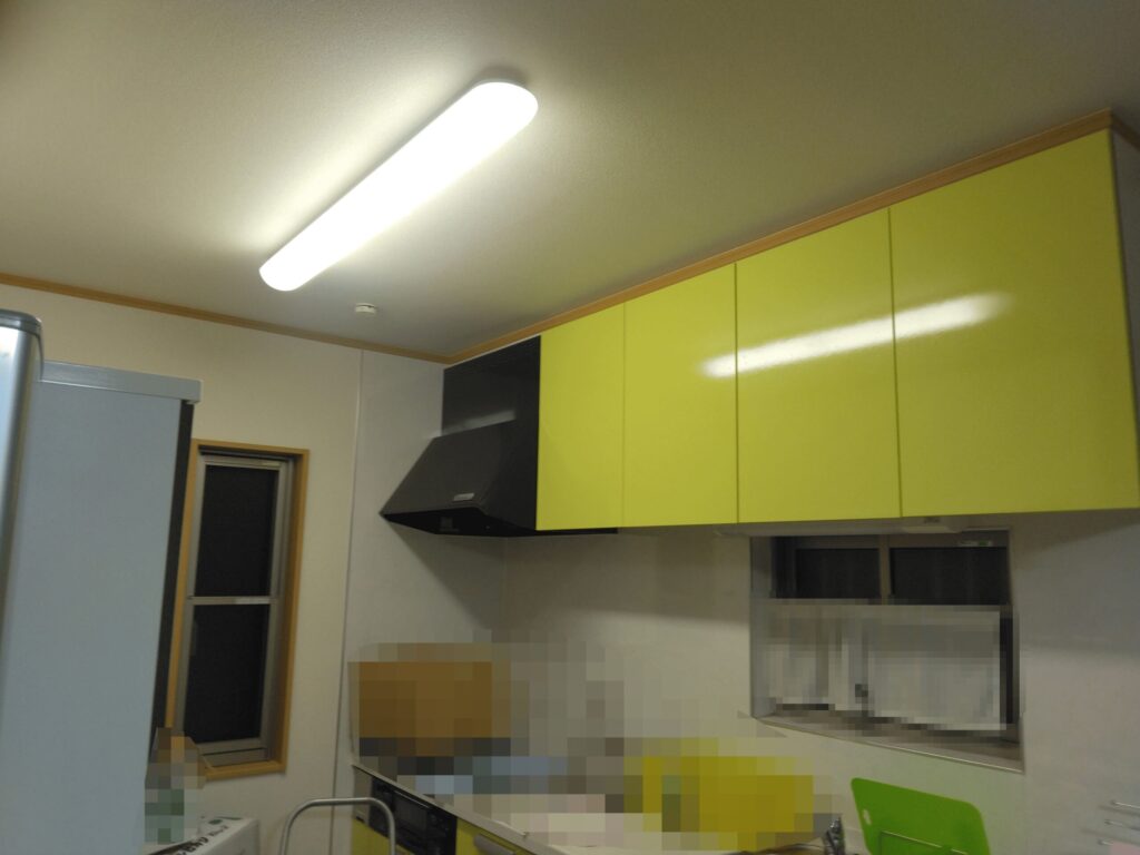 黄緑色の吊り戸棚と黒いレンジフードがある実家のキッチン
